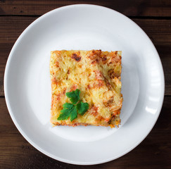 Close-up of a traditional lasagna topped with parskey leafs served on a white plate