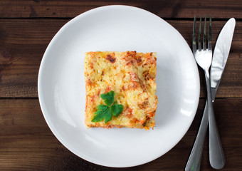 Close-up of a traditional lasagna topped with parskey leafs served on a white plate