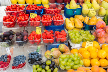 VENICE, ITALY -SEPTEMBER 2016, market. Fishmonger at work. On price tags label price for 1 kg pears, 1 kg plums, strawberries