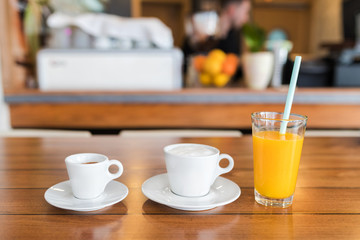 Espresso, cappuccino and glass of fresh orange juice on the table.