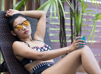 Woman with drink sunbathing on lounger - obrazy, fototapety, plakaty