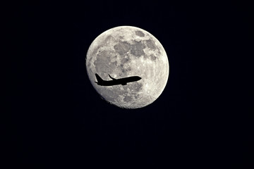 an airplane flying across a moon at night sky - Moon with silhouette Airplane.