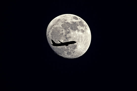 an airplane flying across a moon at night sky - Moon with silhouette Airplane. - Powered by Adobe