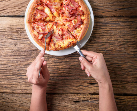 Cutting a delicious Italian pizza with cheese, mushrooms, artich