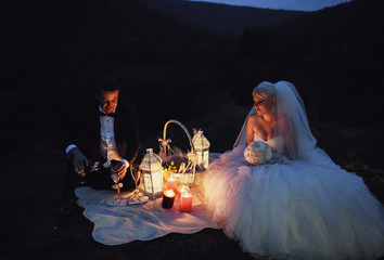 Beautiful stylish newlyweds on the picnic in the evening