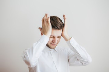 Young man with headache keep his head on a light background