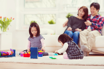Naklejka premium Young happy family with pretty daughters playing and having fun