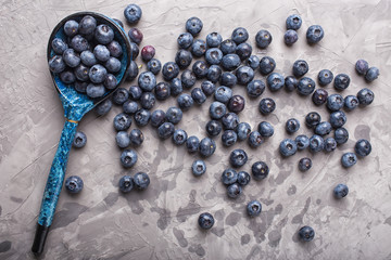 garden blueberries on a concrete background with vintage wooden spoon. Top view