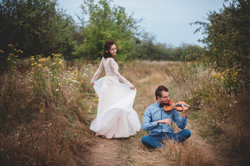 Fototapeta premium Violinist and woman in white dress , young man plays on the violin the background nature,Young hipster musician man playing violin in the nature outdoor lifestyle