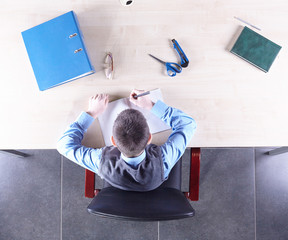 Boy sitting in a chair at the office table. Top view