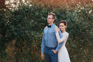 Sunshine portrait of happy bride and groom outdoor in nature location at sunset. Warm summertime