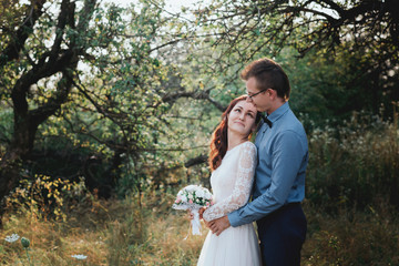 Just married loving hipster couple in wedding dress and suit on a green field in the woods. happy bride and groom walking running and dancing on a summer meadow. Romantic married to a young family