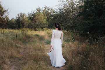 Yong bride spinning in a white dress on the bank on nature.Dress develops in the wind. Happy bride in a wedding dress is spinning.