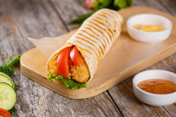 Tortilla with chicken and tomatoes on a wooden stand