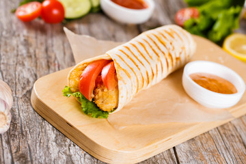 Tortilla with chicken and tomatoes on a wooden stand