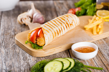 Tortilla with chicken and tomatoes on a wooden stand