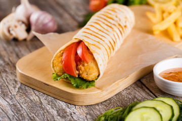 Tortilla with chicken and tomatoes on a wooden stand