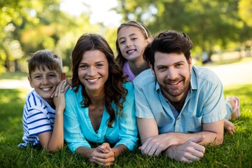 Portrait of happy family lying on grass in park