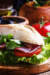 Sandwich with ham, lettuce and tomato in wheat bun, vintage wood