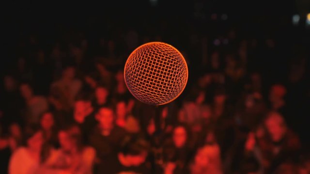 Close-up-microphone on stage and fans waits perfomance on blurred background