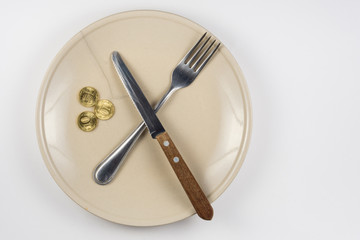 An empty cracked plate with knife and fork, it is based on three ten-coin