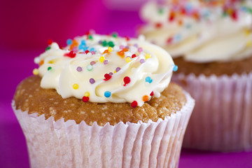 Cupcakes with white cream on the pink background,
