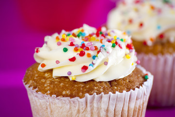 Cupcakes with white cream on the pink background,