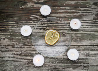 Obraz na płótnie Canvas The dried lemon is surrounded of candles on wooden table