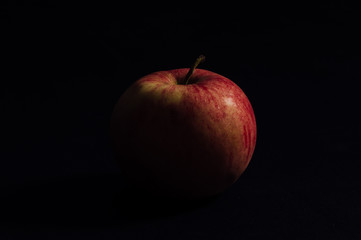Red apple in the shade on a black background. Isolated.