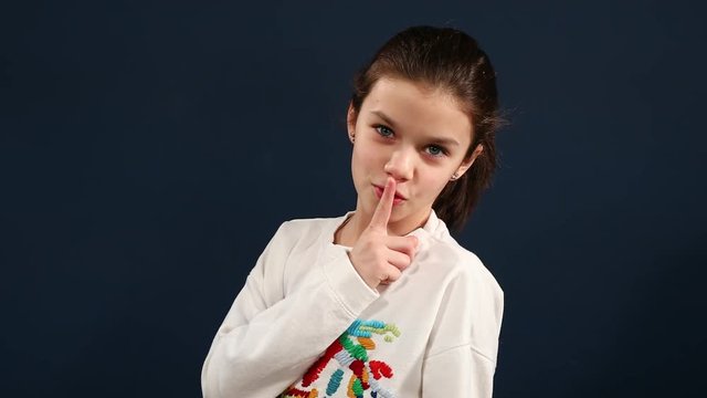 Closeup portrait of a little girl making silence sign with finger on her lips. Video resolution of 4K