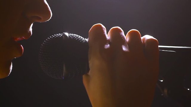 Dolly footage of a woman singing to a microphone.