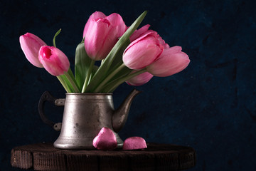 Fresh pink tulip flowers bouquet in old teapot with chocolate heart. View with copy space Spring holiday concept