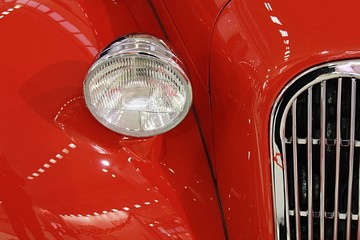 Detail of head light bucket and chrome grill on red veteran roadster