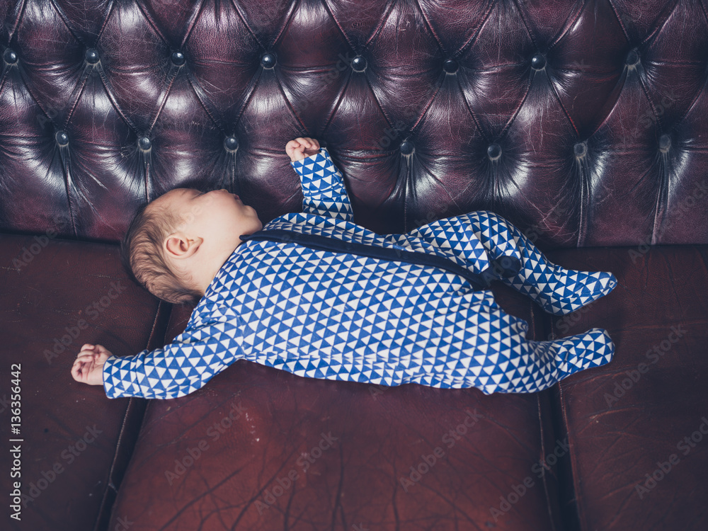 Wall mural Baby sleeping on a leather sofa