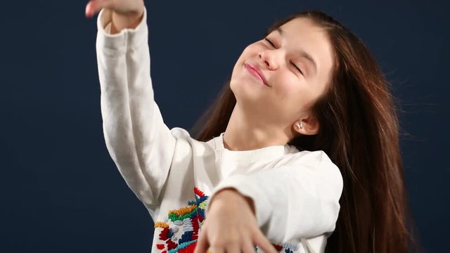 Portrait of a beautiful little girl with arms on the air, isolated blue background. Video resolution of 4K