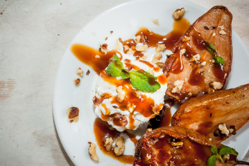 Fresh summer salad - grilled pears, ice cream with walnuts and caramel sauce. On the grey stone concrete table. Close view