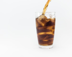 soft drink pouring from a plastic bottle into a glass filled with ice cubes and cola