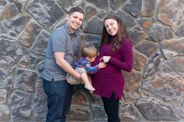 Family Portrait with a toddler kissing a pregnant women's belly.