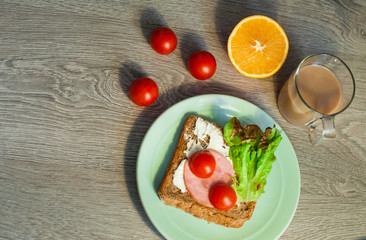 Sandwich with bacon, ham and cheese for breakfast. Coffee cappuccino. On a wooden background