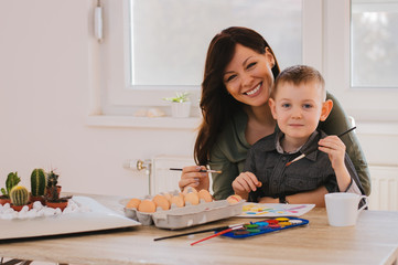 Mother and her son painting Easter eggs. Happy family preparing