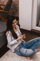 Woman sitting on the floor using mobile phone