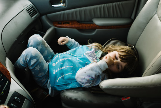 Young girl in car, lying in passenger seat, sucking thumb