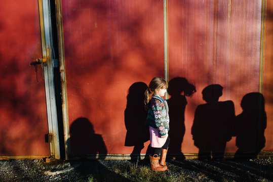 Girl standing in shadows of other children