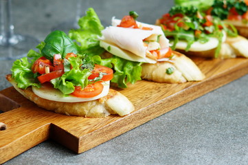 Italian bruschetta with roasted tomatoes, mozzarella cheese and herbs on a cutting board