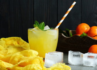 refreshing juice from tangerines with ice cubes and mint on a gray stone background. rustic