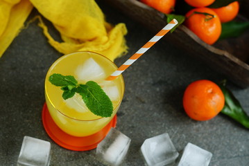 refreshing juice from tangerines with ice cubes and mint on a gray stone background. rustic