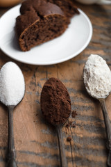 Cake, flour, sugar, cocoa, milk and eggs on a wooden table. Ingredients for cooking.