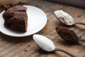 Cake, flour, sugar, cocoa, milk and eggs on a wooden table. Ingredients for cooking.