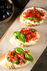 Tomato and cheese fresh made bruschetta. Italian tapas, antipasti with vegetables, herbs and oil on grilled ciabatta and baguette bread.