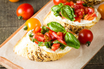 Tomato and cheese fresh made bruschetta. Italian tapas, antipasti with vegetables, herbs and oil on grilled ciabatta and baguette bread.